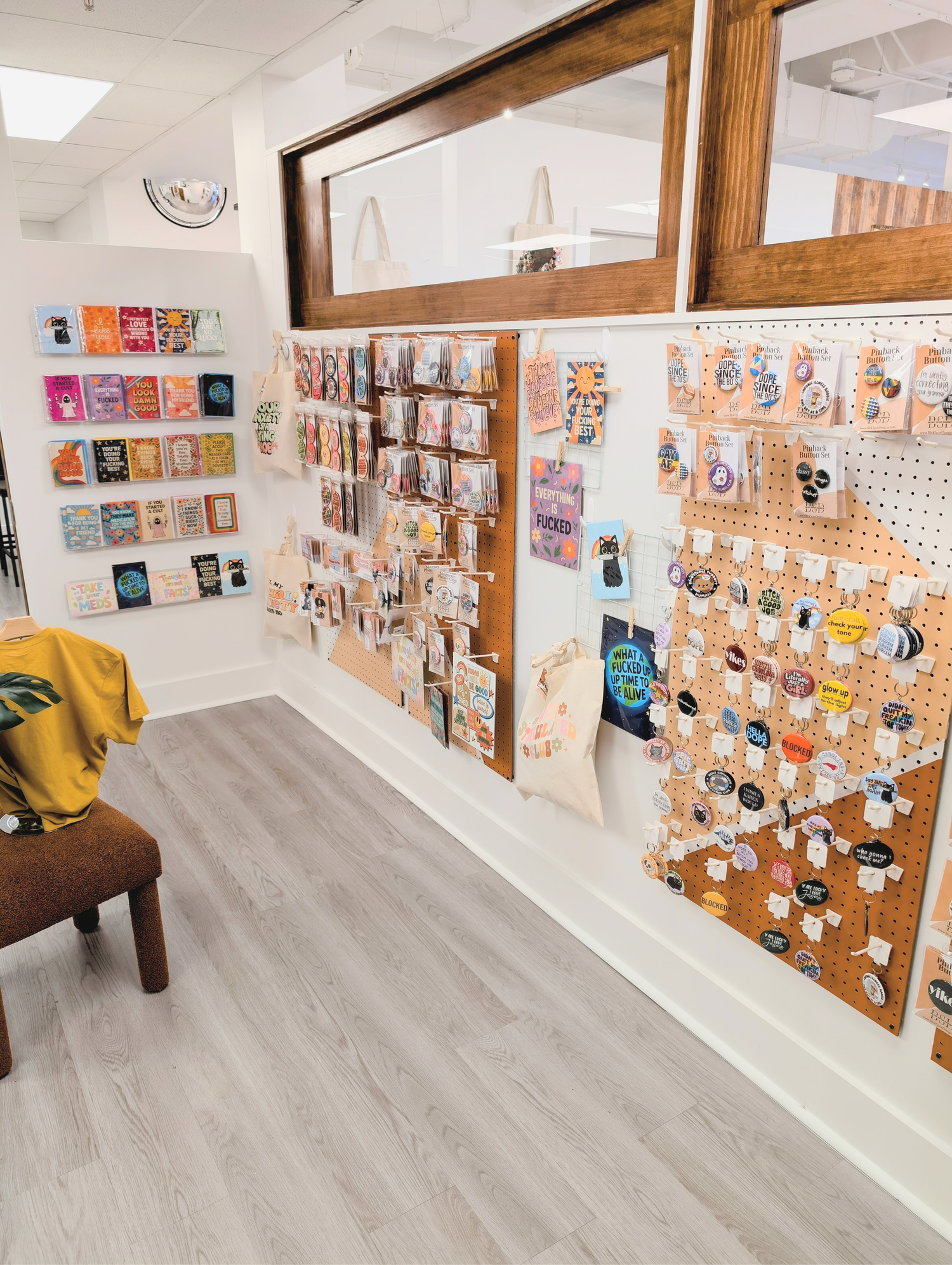 Store interior with merchandise on display, including cards and pins, on a pegboard wall.